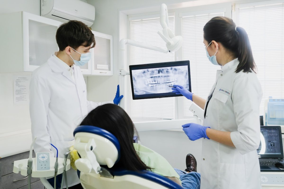 dos profesionales enseñándo una radiografía dental a un paciente